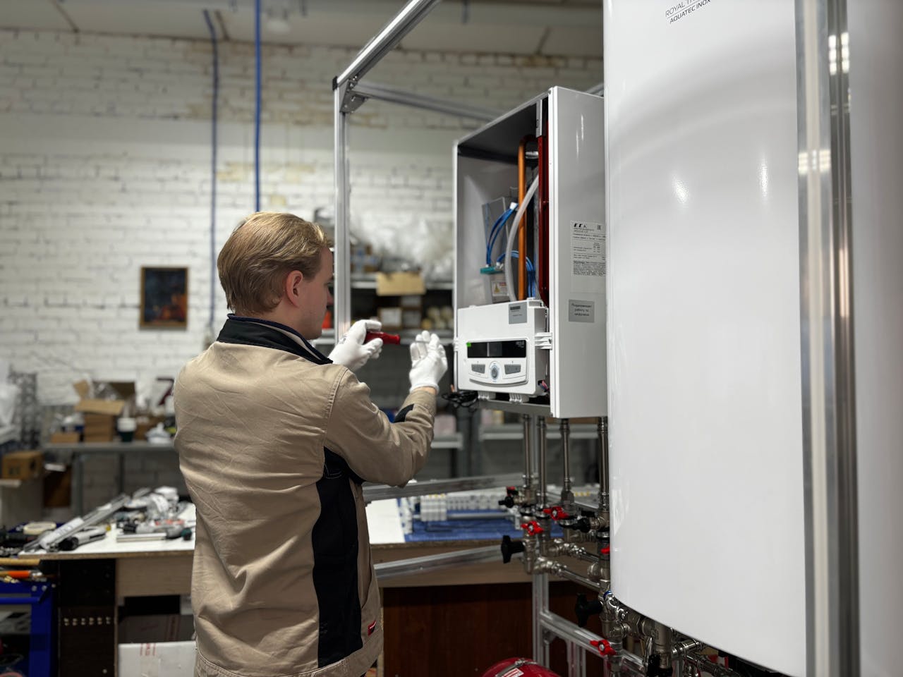 Services-03 Technician inspects and repairs a heating system in an industrial workshop setting.